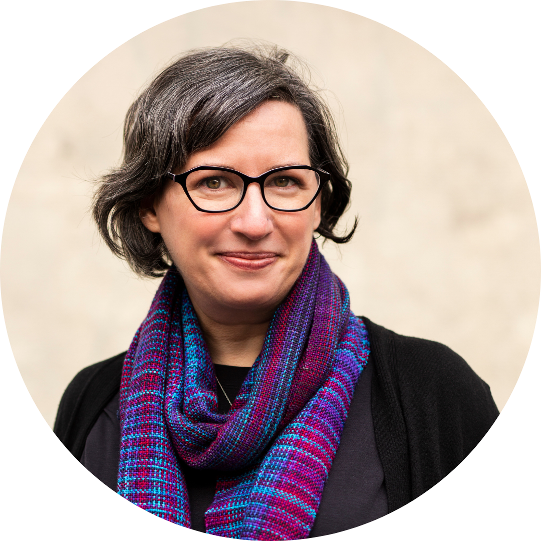 Kim Werker head shot: a white woman with greying dark-brown hair and glasses, wearing a black top and a jewel-tone scarf.